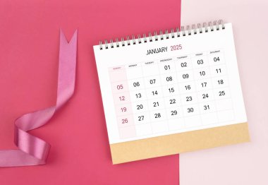 Ocak 2025 Masa takvimi ve pembe arkaplan üzerine pembe kurdele.