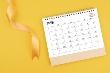 Nisan 2025 sarı kurdeleli masa takvimi düz yatıyordu..