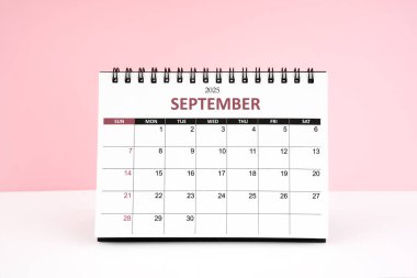Eylül 2025 Masa takvimi pembe arkaplanlı beyaz masada.