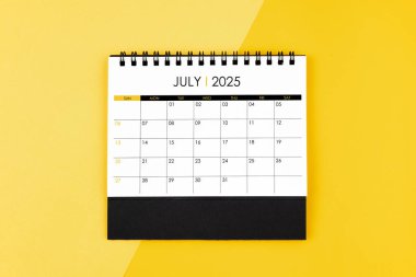 Randevu almak için 2025 yılı Temmuz ayının masa başı takviminin üst görünümü sarı zemin üzerinde.