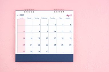 Pembe arkaplanlı ve kopyalama alanı olan Nisan 2025 masa takviminin tam üstünde.