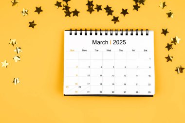 Mart 2025 takvimi ve sarı arka planda parlayan sarı konfeti yıldızları.