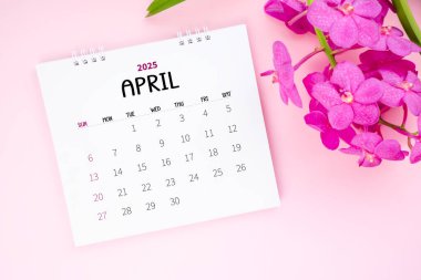 Pembe arka planda bir Nisan 2025 masa takvimi ve pembe orkide.