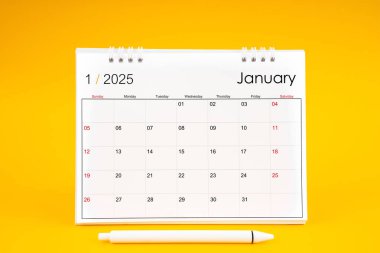 Ocak 2025, 2025 yılı için aylık masa takvimi ve sarı arkaplan üzerine kalem.