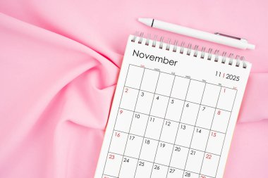 Kasım 2025 takvim ve pembe kumaşlı kalem. Aylık takvim kavramı.