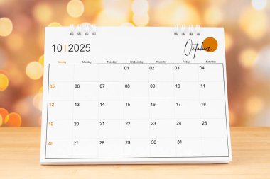 Ekim 2025 masa takvimi ahşap masa üzerinde altın ışıklı bokeh arka plan. Yeni Yıl Konsepti.