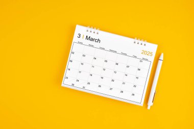 Mart 2025, 2025 yılı için aylık masa takvimi ve sarı arkaplan üzerine kalem.