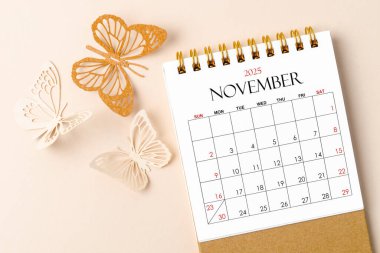 Kasım 2025 Sarı zemin üzerinde planlamak ve hatırlatmak için düzenleyici için masa takvimi ve kelebek kağıt.