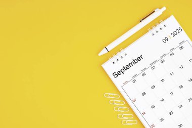 Eylül 2025, 2025 yılı için aylık masa takvimi ve sarı arka planda ataçlı kalem. Kopyalama alanı olan konum.