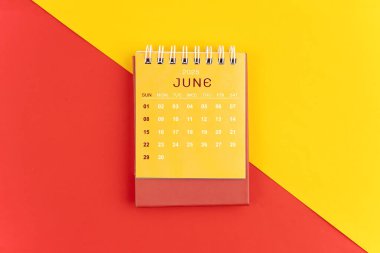 Kırmızı ve sarı arkaplan üzerine Haziran 2025 masa takvimi.
