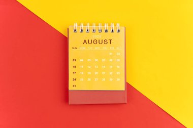 Kırmızı ve sarı arkaplan üzerine Ağustos 2025 masa takvimi.
