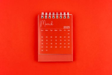 Kırmızı zemin üzerinde kırmızı renkli masa takvimi, Mart 2025 düz yatıyordu.