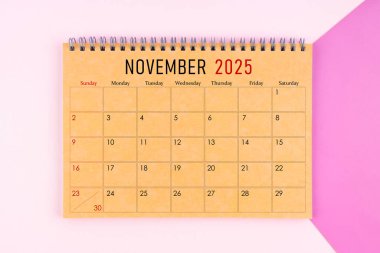 Kasım 2025 Mor arkaplan üzerine kahverengi kağıt sayfasından yapılmış masa takvimi.