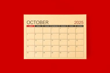 Ekim 2025 Masa takvimi kırmızı arkaplan üzerine kahverengi kağıt sayfasından yapılır.