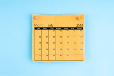 July 2025 brown calendar with wooden thumbtack on blue color background.