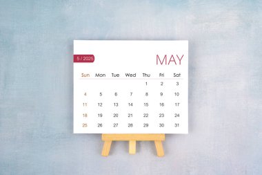 May 2025 calendar page with wooden easel, Flat lay.