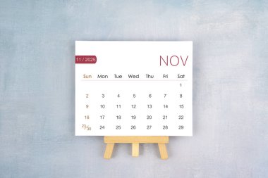 November 2025 calendar page with wooden easel, Flat lay.