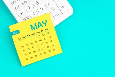 Mavi arkaplan üzerinde hesap makinesi olan 2025 takvim sayfası.