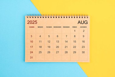 2025 Ağustos 'unun kahverengi takvimi mavi ve sarı arka plan üzerine.