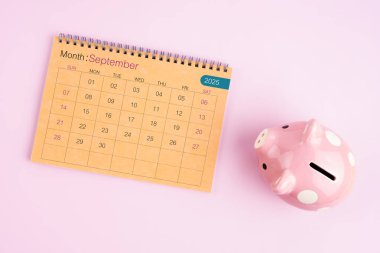 Eylül 2025 için kahverengi masa takvimi ve pembe domuz kumbarası.