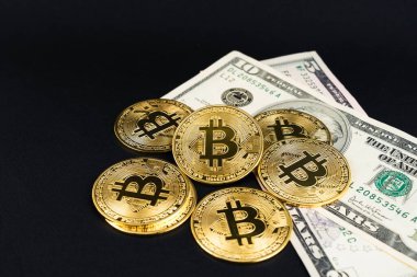Siyah deri arka planda USD banknotları olan bir yığın bitcoin..