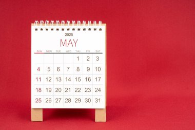 Kırmızı arkaplanda Mayıs 2025 için boş masa takvimi.