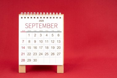 Kırmızı arkaplan üzerine Eylül 2025 için boş masa takvimi.