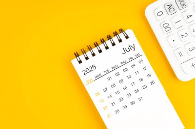 Sarı zemin üzerinde Temmuz 2025 takvim ve hesap makinesi, düz yatıyordu.
