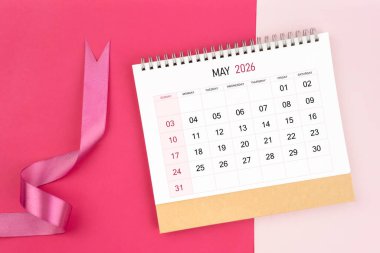 Mayıs 2026 Masa takvimi ve pembe renk arkaplanı üzerine pembe kurdele.