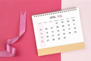 Nisan 2026 Masa takvimi ve pembe renk arkaplanı üzerine pembe kurdele.