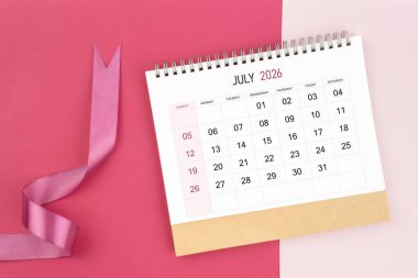 Temmuz 2026 masa takvimi ve pembe renk arkaplan üzerine pembe kurdele.