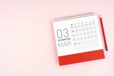 Üst görünüm Mart 2026 masa takvimi ve kırmızı kalem, kopya alanı olan konum.