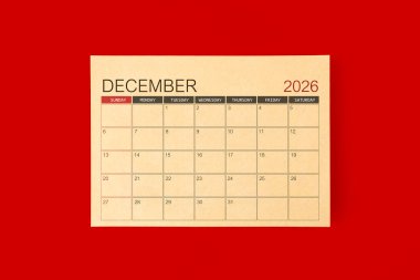 Aralık 2026 Masa takvimi kırmızı arkaplan üzerine kahverengi kağıt sayfasından yapılır.