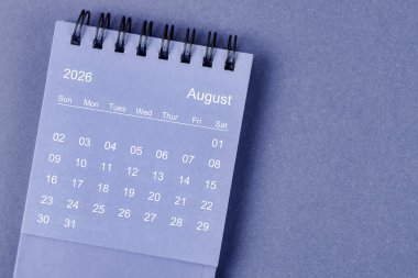 2026 Ağustos ayının masa takvimi mavi arkaplan üzerine.