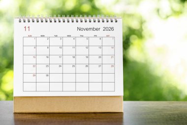 Doğanın arka planındaki ahşap masa üzerinde organizatörün planlaması ve hatırlatması için Kasım 2026 takvim masası.
