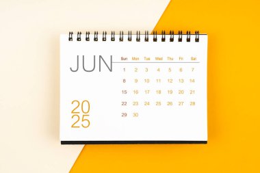 Sarı arkaplan üzerine Haziran 2025 için masa takvimi, düz yatıyordu.