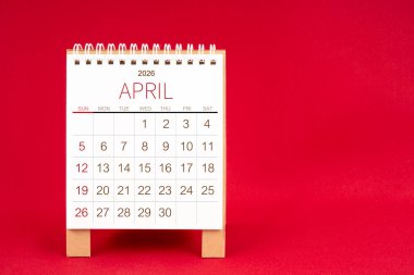Kırmızı arkaplan üzerine Nisan 2026 için boş masa takvimi.