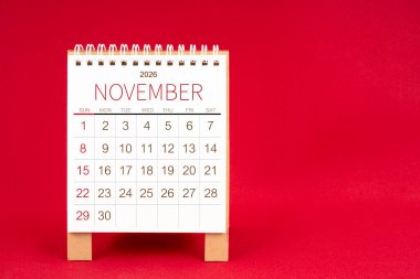 Kırmızı arkaplan üzerine Kasım 2026 için boş masa takvimi.