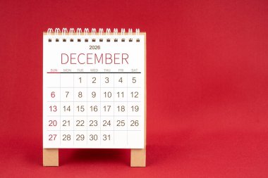 Aralık 2026 için kırmızı arkaplan üzerine boş masa takvimi.