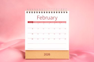 Pembe renkli tekstil üzerine boş Şubat 2026 masa takvimi ön görünümü.