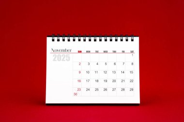 Kasım 2025 Kırmızı arkaplan üzerine boş masa takvimi.