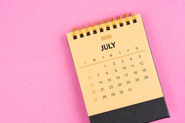 Pembe arka planda Temmuz 2025 için kahverengi masa takvimi.
