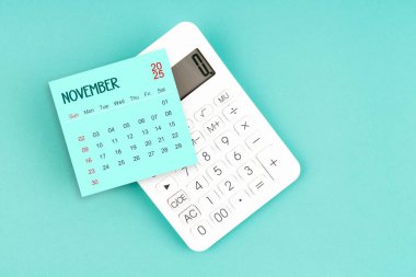 Mavi arkaplanda hesap makinesi olan Kasım 2025 takvim kartı.