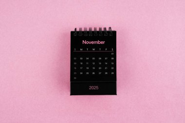 Pembe arka planda Kasım 2025 için siyah takvim.