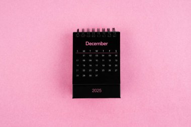 Pembe arka planda Aralık 2025 için siyah takvim.