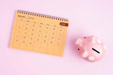 Haziran 2026 için kahverengi masa takvimi ve pembe kumbara.