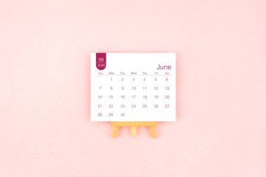 Pembe arka planda ahşap sehpası olan Haziran 2026 takvim sayfası.