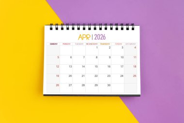 2026 Nisan ayının masa takvimi sarı ve mor arka planda 2026 yılı için.