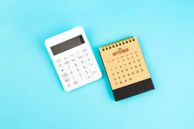 Eylül 2026 mavi zemin üzerinde kahverengi kakülatör ve beyaz hesap makinesi.