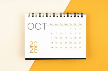 Sarı arkaplan üzerine Ekim 2026 için masa takvimi.